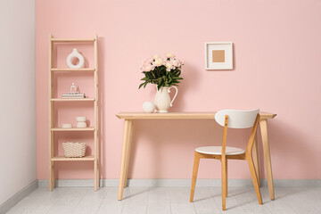 Shelving unit, chair, table and vase with beautiful peony flowers near pink wall in interior of room