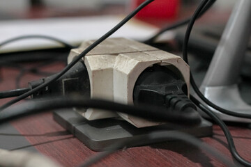 Close-up view of an electrical power strip with multiple plugs and tangled cables