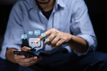 Close-up of man's hand using smartphone to play social media with emoticons or notifications popup.	
