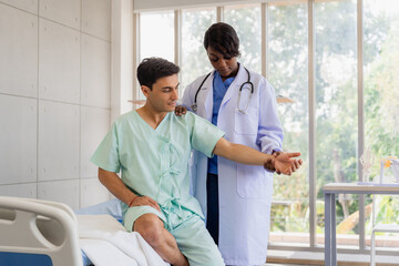 A female doctor examining a patient's arm and a nurse assisting him with a walker during a physical therapy session. 