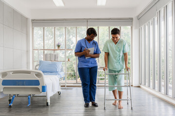 Therapist assisting a patient in learning to walk with crutches and a walker during a...