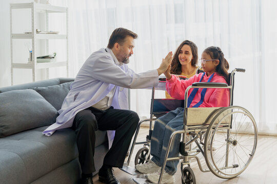 Caring doctor making a house call to encourage a young disabled girl in a wheelchair, with her mother's support. Home healthcare specialist showing test results on a tablet to a child - Powered by Adobe