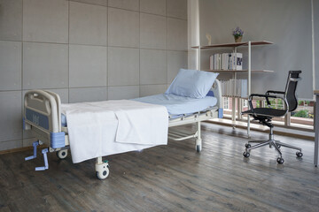 Empty hospital room with a patient bed and a wheelchair by the window, conveying recovery or...