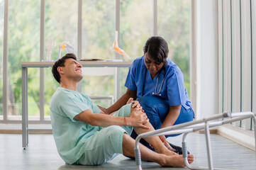 Male patient falling down with knee pain during a physical therapy session, with a nurse rushing to...