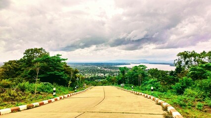 A winding road descends from Wat Phu Salao viewpoint in Pakse, Laos, revealing a breathtaking...