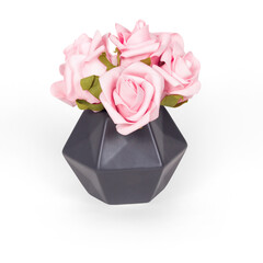 A geometric vase holding pink artificial roses, ideal for home decor or gifting.
