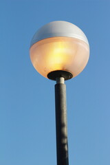 street lamp on blue sky. one night lamp post shines with a faint light on a blue background 