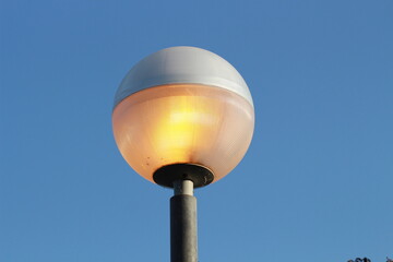 street lamp on blue sky. one night lamp post shines with a faint light on a blue background 