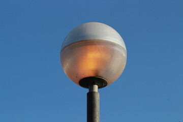 street lamp on blue sky. one night lamp post shines with a faint light on a blue background 
