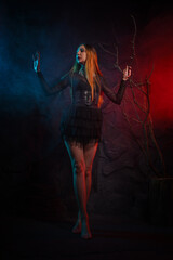 Beautiful vampire woman posing in an old crypt illuminated by candlelight background.