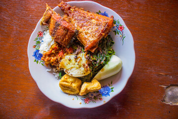 nasi tempong or sego tempong is traditional food from banyuwangi, indonesia made from rice, traditional fried squid, fried eggplant, cucumber slices, vegetables, spinach and spicy sambal (sauce) chili