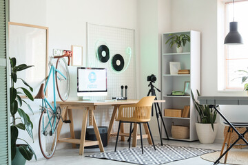 Interior of light podcaster's studio with workplace, synthesizer and bicycle