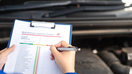 Action of a repairman is checking on multi-point checklist form during perform service the car...