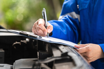 Action of a repairman is checking on multi-point checklist form during perform service the car...