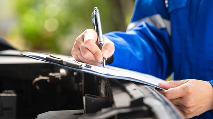 Action of a repairman is checking on multi-point checklist form during perform service the car...
