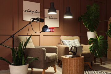 Interior of podcaster's studio with armchairs, plants and glowing lamps