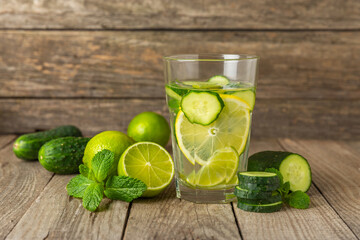 Cucumber water with lemon, lime and mint on a wooden table. Water infused with sliced...