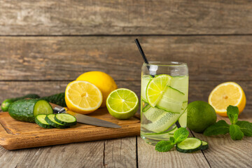 Cucumber water with lemon, lime and mint on a wooden table. Water infused with sliced...