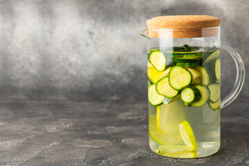 Cucumber water with lemon, lime and mint on a wooden table. Water infused with sliced...
