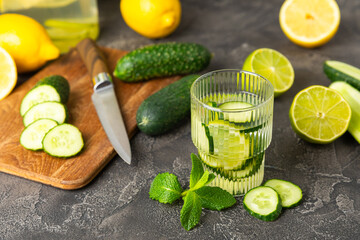 Cucumber water with lemon, lime and mint on a wooden table. Water infused with sliced...