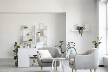 Interior of home office with workplace, bicycle and armchairs