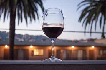 Red Wine Glass Framed by Palm Trees, Lights, and the Hollywood Hills
