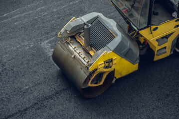 Fototapeta premium Workers lay a new asphalt coating using hot bitumen. Work of heavy machinery and paver. Top view