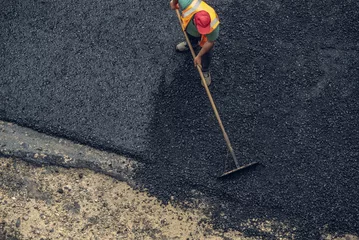 Workers lay a new asphalt coating using hot bitumen. Work of heavy machinery and paver. Top view © Artem