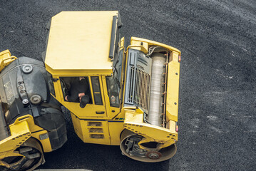 Workers lay a new asphalt coating using hot bitumen. Work of heavy machinery and paver. Top view