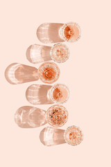 Top view many glasses of rose wine on peach color background, beautiful shadow at sun. Vintage...