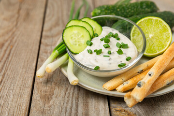Cucumber sour cream tzatziki sauce on a wooden table.Tartar sauce. Traditional delicious appetizer....