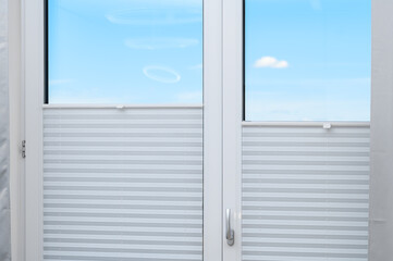 Isolated balcony window with a view covered with gray pleats