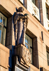 Elegant stone statue holding a globe on the façade of the South Africa House in Trafalgar Square, London. A symbol of international presence and diplomacy, captured in warm sunlight.