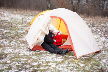 Winter camping adventure captured in a cozy tent with joyful children sharing warm moments in the snowy landscape during a chilly day