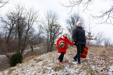 Winter walk with child in red coat exploring snowy landscape near trees during overcast weather in early afternoon