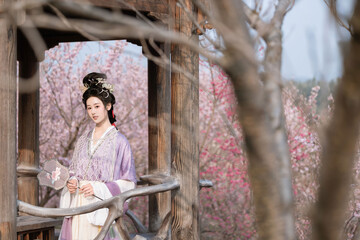 Young Asian woman in traditional attire among cherry blossoms Chinese word means cherry.