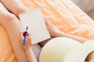 Pregnant woman makes notes in notebook. Concept of pregnancy Mother waiting for baby