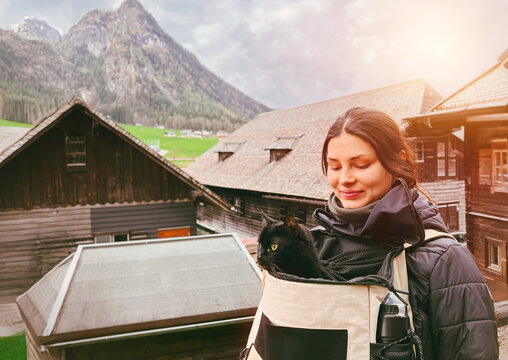Female hiker with black cat in mountain landscape