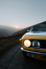 Vintage yellow sports car parked in urban street at dusk, close-up front headlight view of retro vehicle