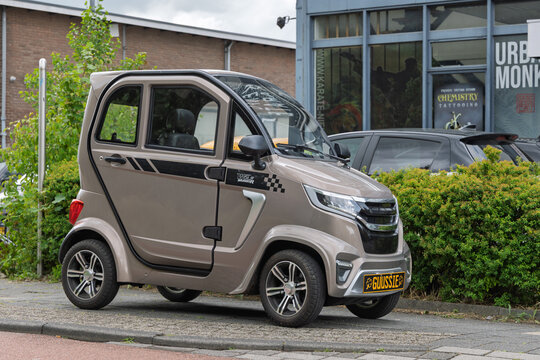 A compact and modern two-seater electric microcar (brommobiel) parked on a city street, featuring distinct stripes. Utrecht, Netherlands, 6 June 2025.