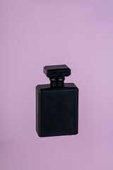 Perfume in beautiful black bottle, isolated on purple background.