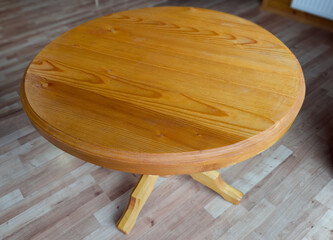 Wooden round single leg table in room with wooden flooring