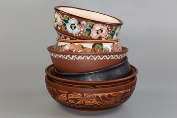 Stacked different empty clay bowls on gray background, front view