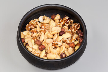 Mixture of different peeled nut kernels in black clay bowl