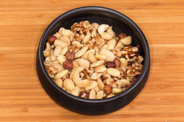 Different peeled nut kernels mixture in bowl on wooden surface
