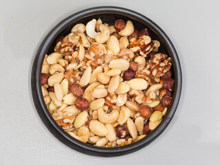 Mixture of different peeled nut kernels in black clay bowl