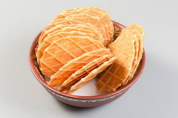 Sweet round wafers in clay bowl on a gray background
