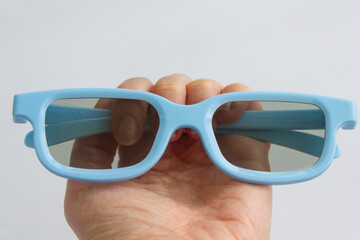 blue glasses, eyes on a person's hand, hand holding 3D glasses, blue colors, 3D glasses for cinema,...