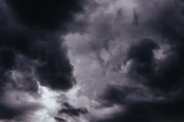 A stormy sky filled with ominous, dark heavy low clouds, creating a dramatic scene. Moody shot of a gloomy grey sky filled with swirling, storm clouds. Stormy weather. Before storm, rainstorm.