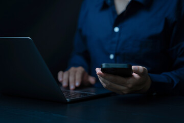 Businessman using mobile smart phone and online working on laptop. surfing the internet, searching the information at office. The focus is on the interaction with technology in a modern.